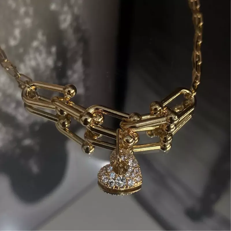 Pulseira de elos com pingente de coração cravejado.